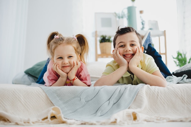 Charming little boy and girl lie on the bed