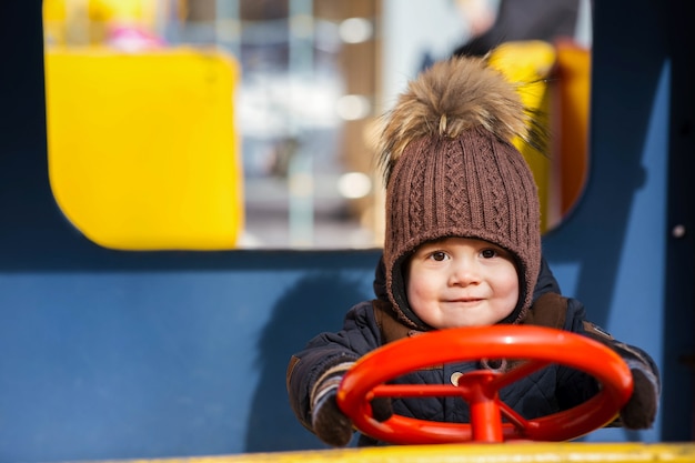 Charming little boy plays in the toy car outside