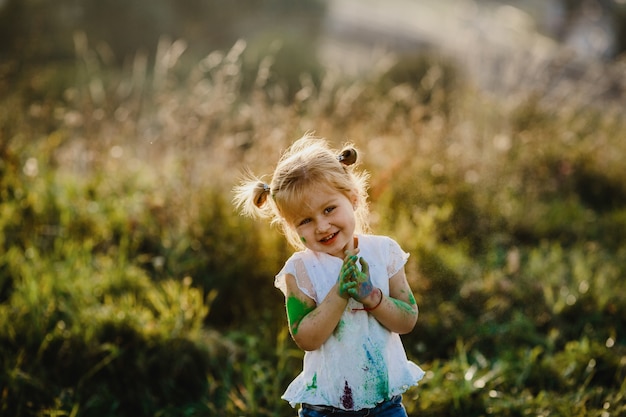 Charming little girl with white shirt covered with different paints