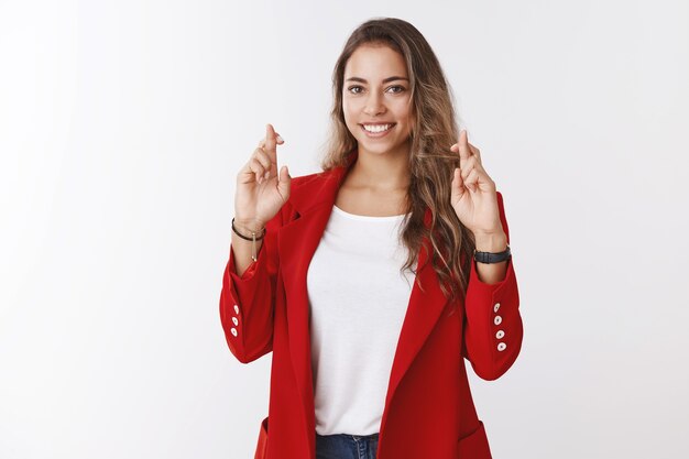 Charming lucky cute woman high hopes pass job interview successfully cross fingers for good luck, hopefully smiling camera praying dreaming anticipating results self-assured, white wall