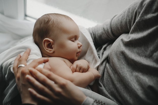 Charming newborn boy sleeps on mother's arms