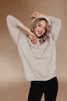 Free photo charming slim lady in brown sweater laughing with eyes closed