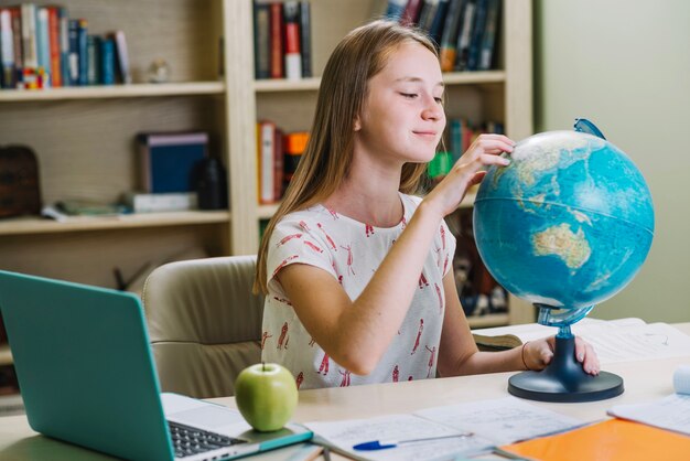 Charming student working with globe at desk