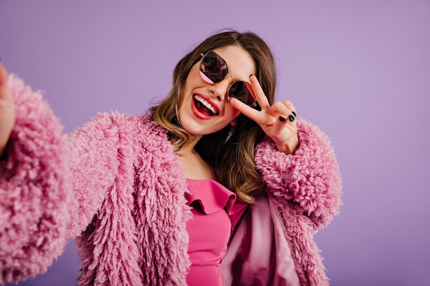 Free photo charming stylish woman posing with smile caucasian girl making selfie in purple coat