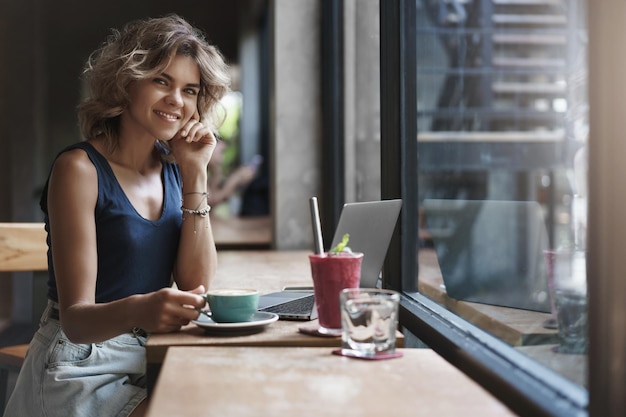 Free Photo charming successful young businesswoman working cafe restaurant sit near window enjoy tasty coffee smoothie use laptop prepare project student studying before university exams