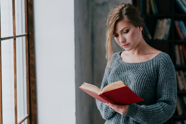 Free photo charming woman enjoying reading near window