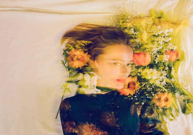 Free photo charming woman between fresh flowers on bed