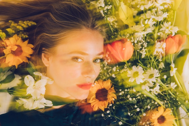 Free photo charming woman between fresh flowers in greenness