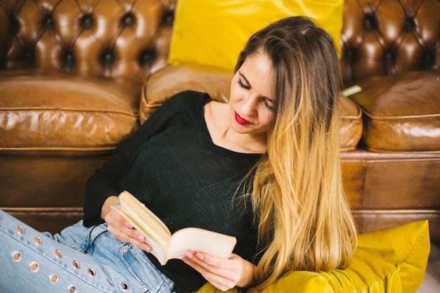 Free photo charming woman reading near sofa