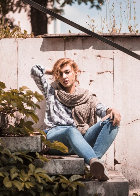 Charming woman sitting on steps and readjusting hairs