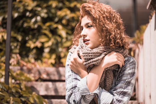 Charming woman sitting on steps with crossing hands 