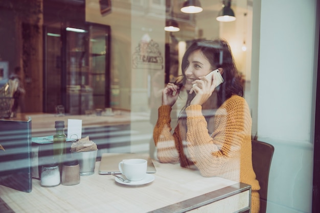 Free photo charming woman speaking on phone in cafe