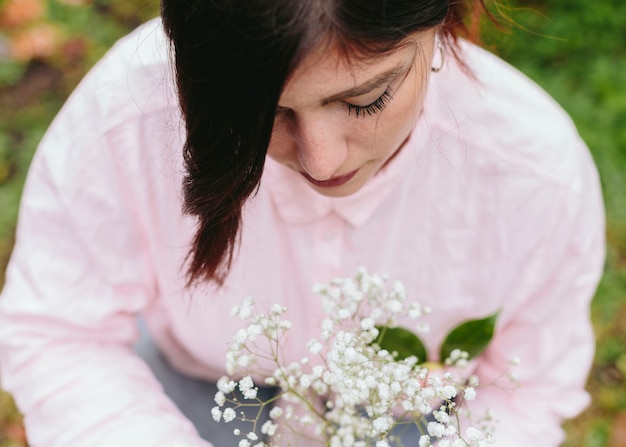 Free photo charming woman with bunch of plant with white blooms