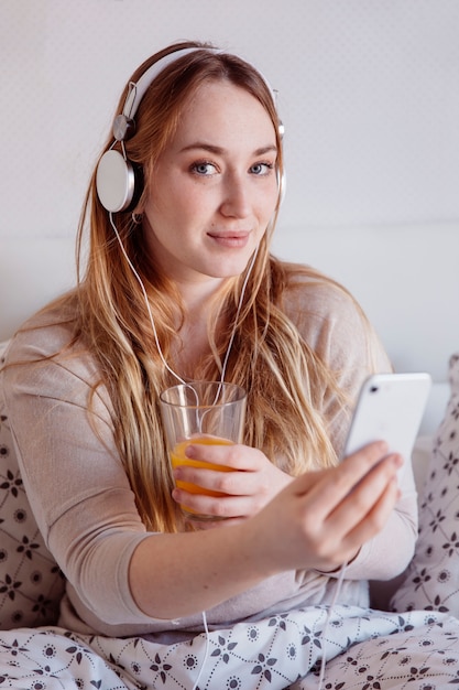 Free Photo charming woman with juice and smartphone