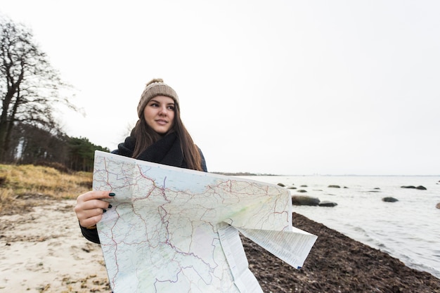 Free photo charming woman with map walking on coast