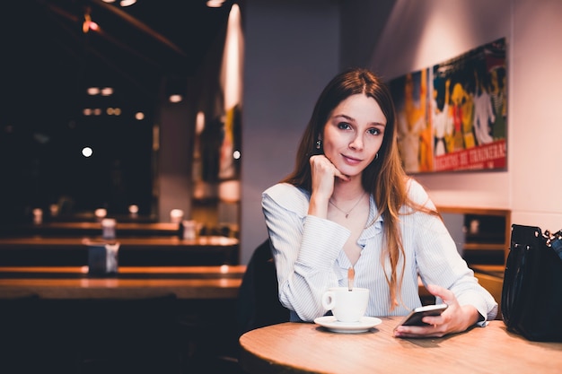 Charming woman with smartphone looking at camera