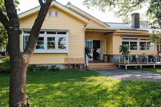 Free photo charming yellow house with wooden windows and green grassy garden