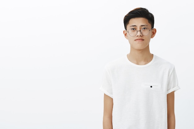 Free Photo charming young chinese guy in trendy glasses and t-shirt standing to right side of copy space with friendly expression