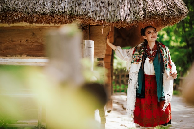 Free Photo charming young girl in a colored embroidered dress poses near the house