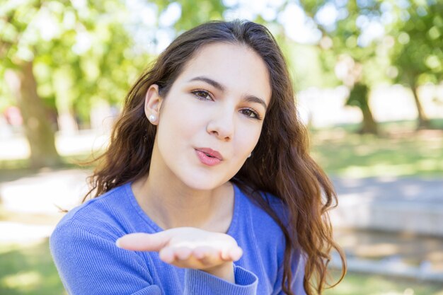 Charming young woman blowing air kiss