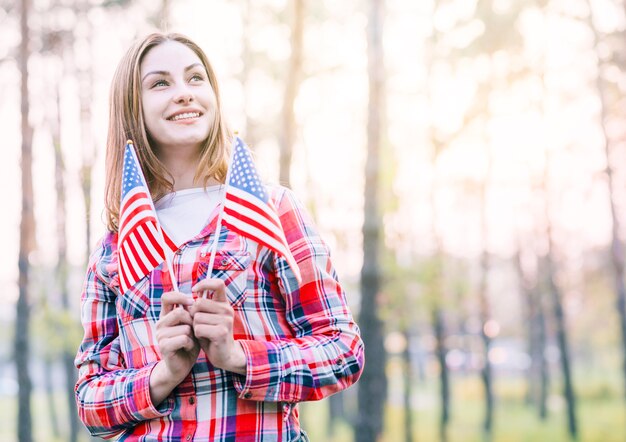 Charming young woman holding small American flags