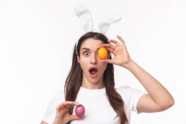 charming young woman in rabbit ears holding colored egg