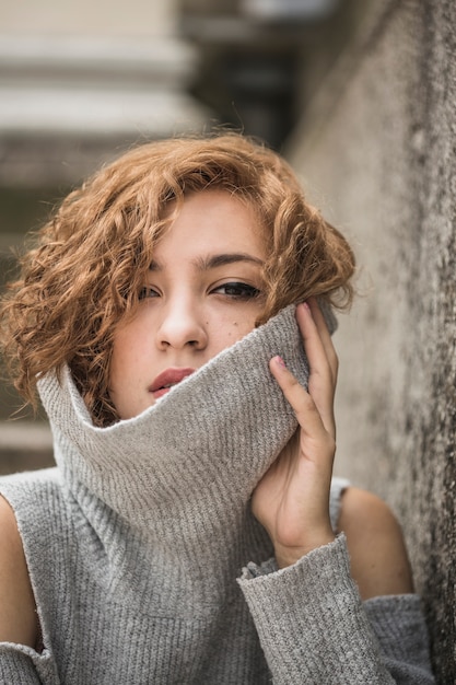 Free photo charming young woman with short tufty hair holding raised sweater's collar