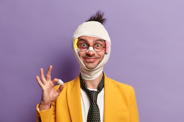 Free Photo cheerful adult man has trauma of head, broken nose and bruises under eyes