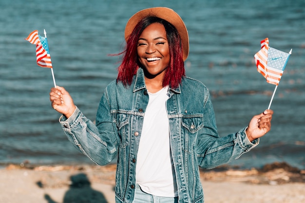 Free photo cheerful african american woman holding american flags