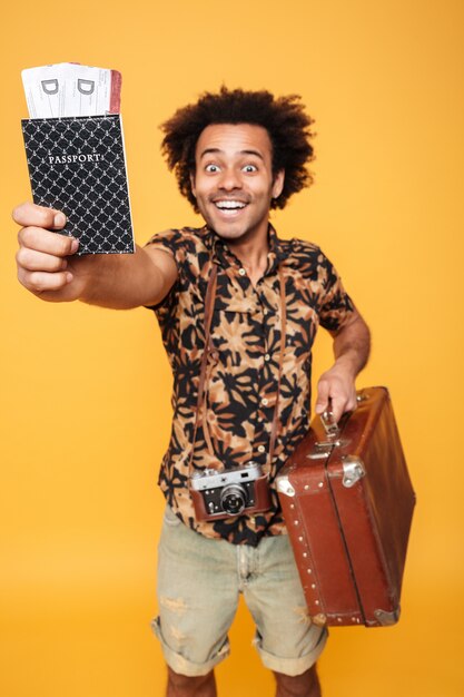 Cheerful african man holding passport and suitcase