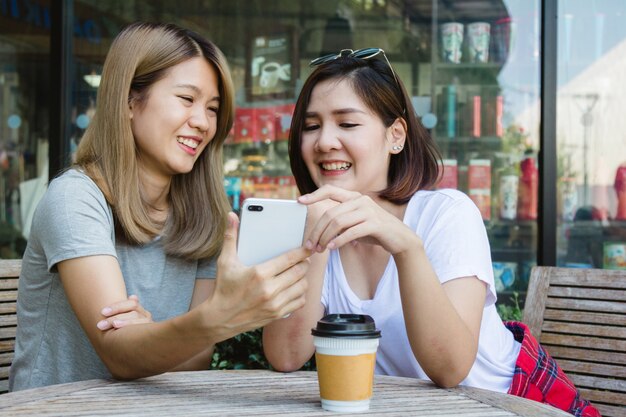 Cheerful asian young women sitting in cafe drinking coffee with friends and talking together. Attrac