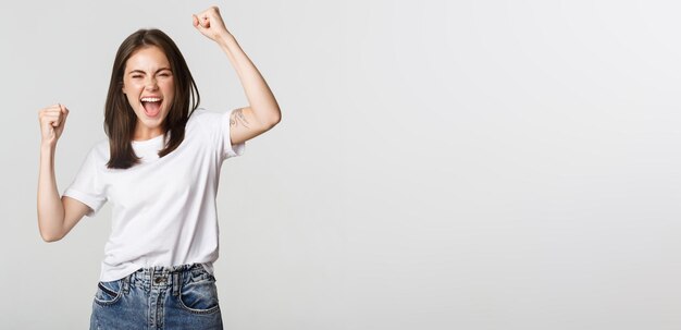 Cheerful attractive brunette girl fist pump and smiling with rejoice winning