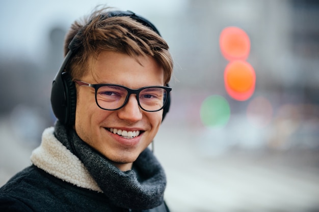 Free Photo cheerful attractive man listening to music in earphones, outdoors. 