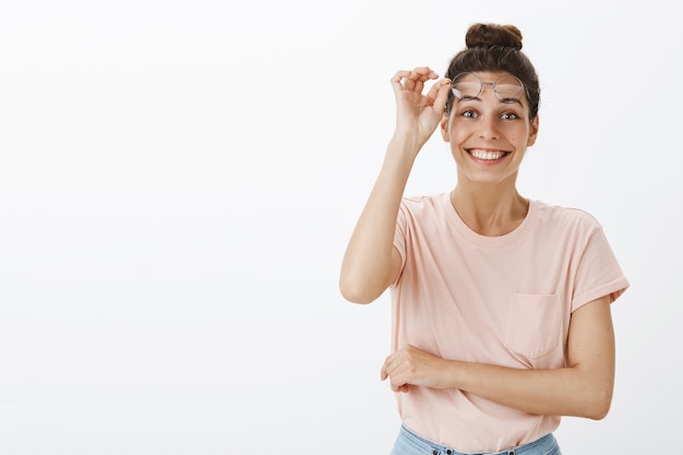 Cheerful attractive young stylish woman posing against the white wall