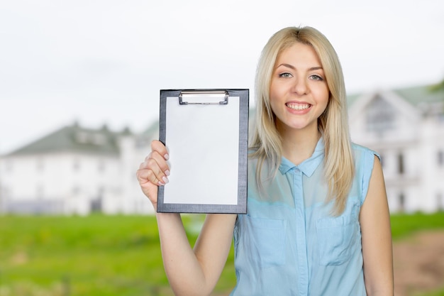 Cheerful attractive young woman showing blank clipboard