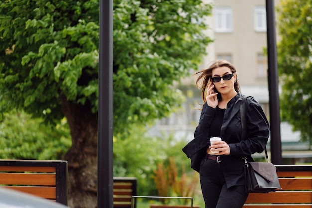 Cheerful beautiful brunette woman in good mood use phone outside