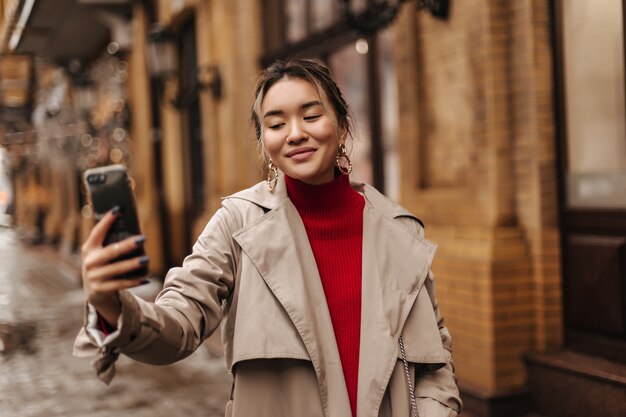 Cheerful blond woman makes selfie walking in European city