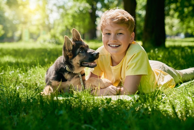 Cheerful boy and german shepherd puppy playing at park