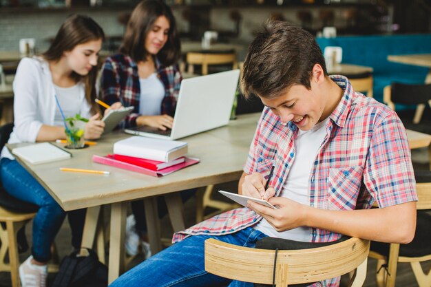 Cheerful boy with tablet and classmates