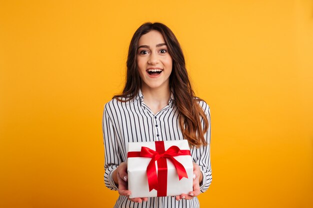 Cheerful brunette woman in shirt holding gift box