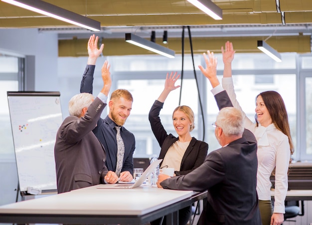 Free photo cheerful business people in the meeting raising the arms