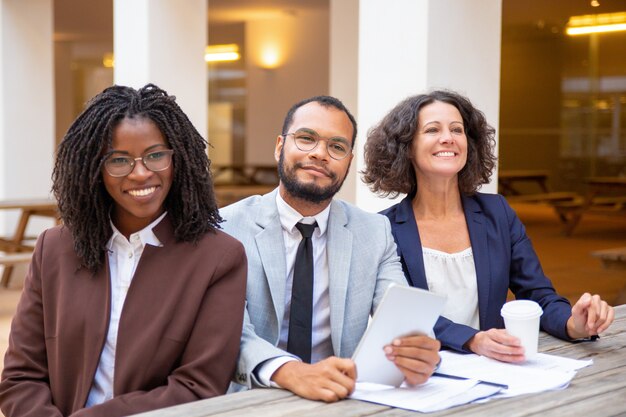 Cheerful business team waiting someone in street cafe