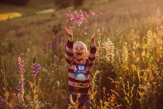 Cheerful child throws petals up posing on the field of lavander 