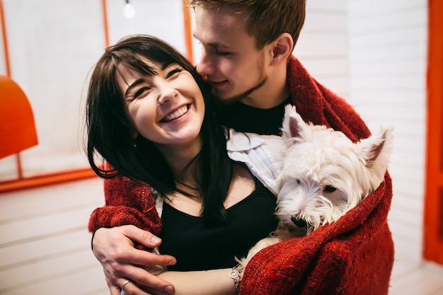 Cheerful couple cuddling with dog in plaid