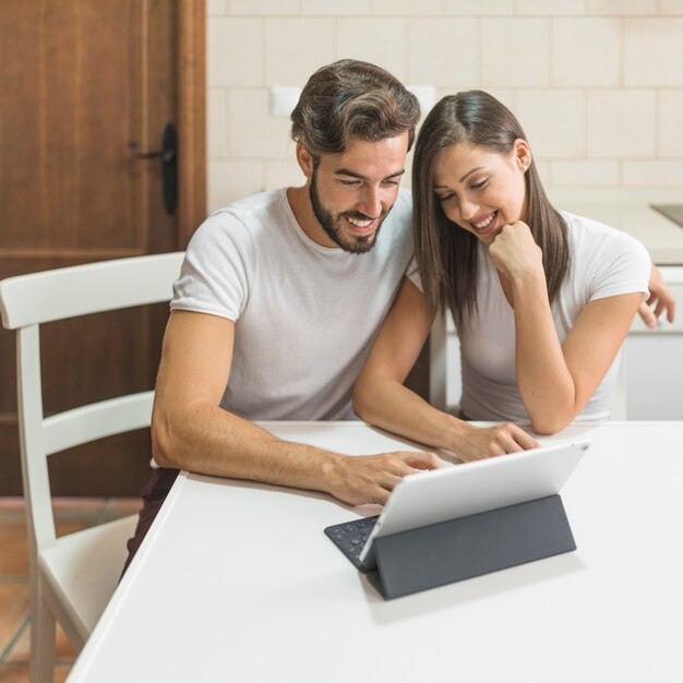 Cheerful couple looking at tablet in kitchen