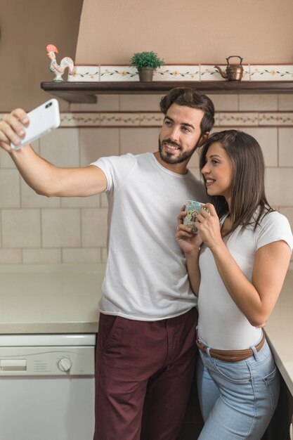 Cheerful couple posing for selfie in kitchen