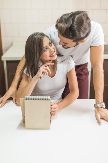 Cheerful couple with notebook looking at each other