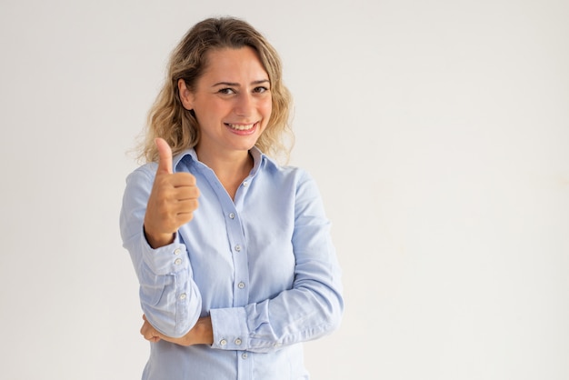 Cheerful excited businesswoman in blue blouse showing thumb-up