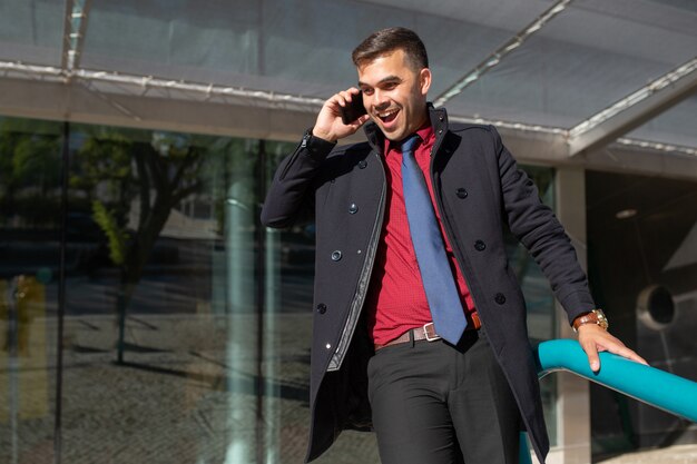 Cheerful excited man talking on phone and moving down stairs