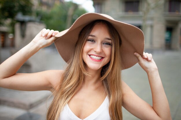 Cheerful excited pretty woman holding edge of hat